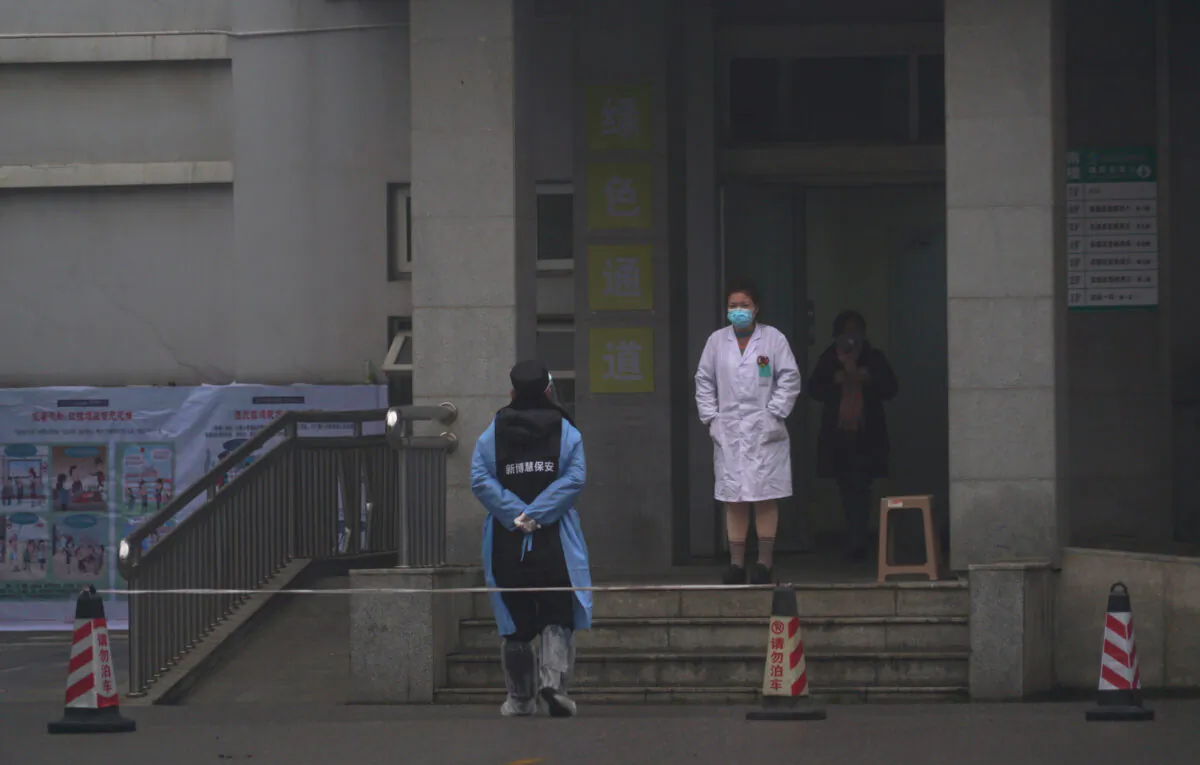 Hospital staff stand outside the emergency entrance of Wuhan Medical Treatment Center, where some infected with a new virus are being treated, in Wuhan, China, on Jan. 22, 2020. (Dake Kang/AP Photo)