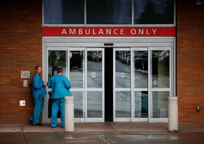 Employees in scrubs talk next to the ambulance entrance at Providence Regional Medical Center after coronavirus victim treated in Everett