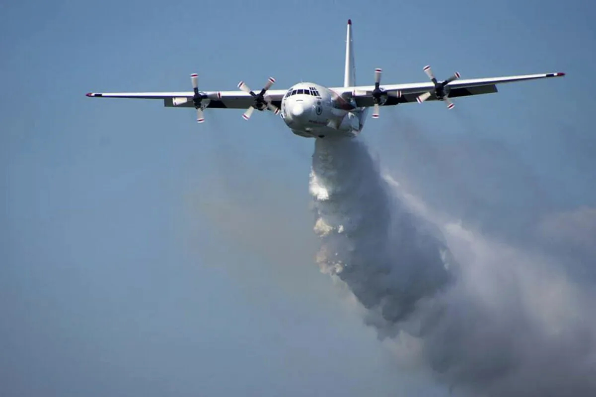 In this undated photo released from the Rural Fire Service, a C-130 Hercules plane called "Thor" drops water during a flight in Australia. Officials in Australia on Jan. 23, 2020, searched for a water tanker plane feared to have crashed while fighting wildfires. (RFS via AP)