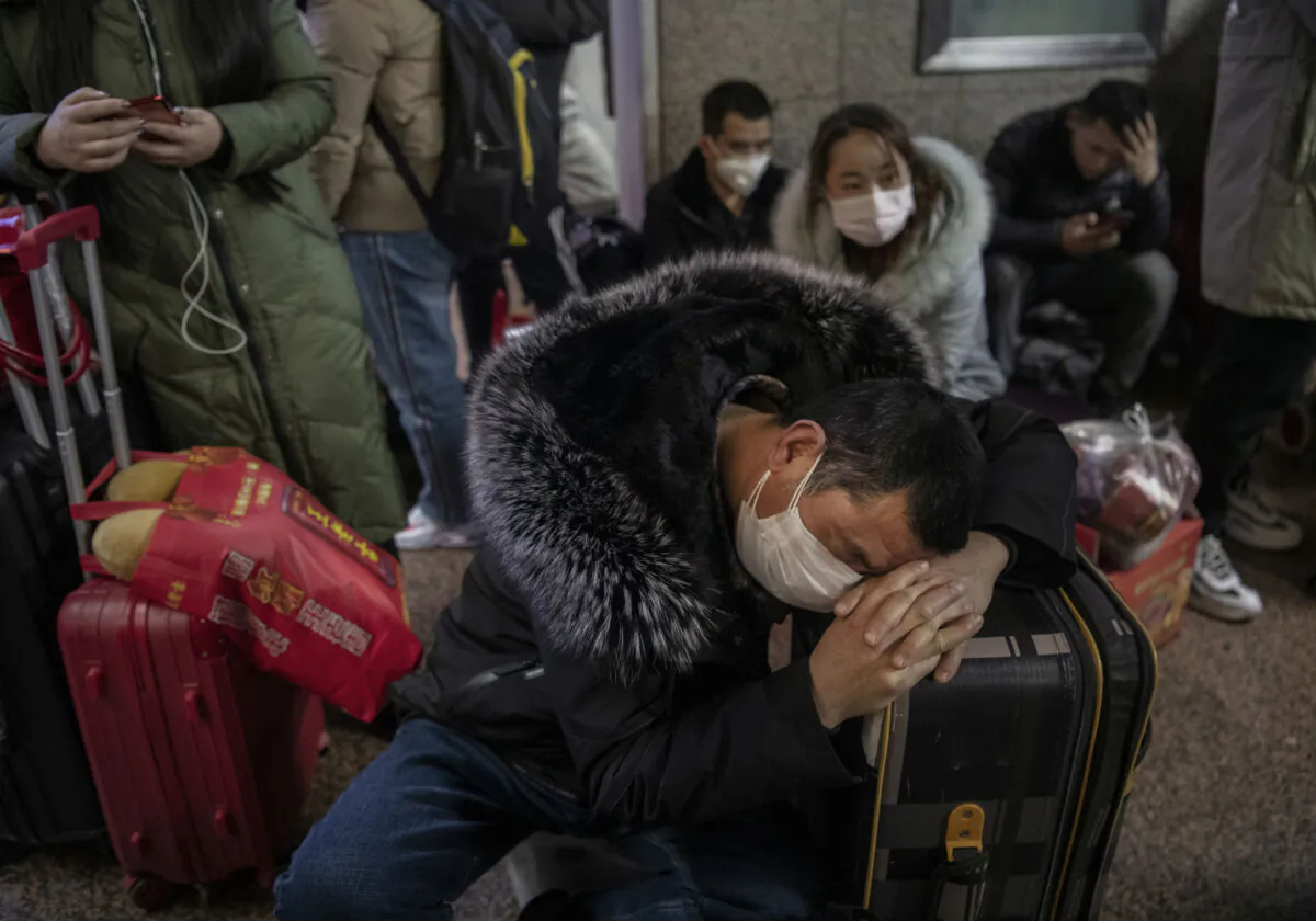 A Chinese man wears a protective mask as he sleeps before boarding a train before the annual Spring Festival at a Beijing railway station in Beijing, China, on Jan. 23, 2020. (Kevin Frayer/Getty Images)