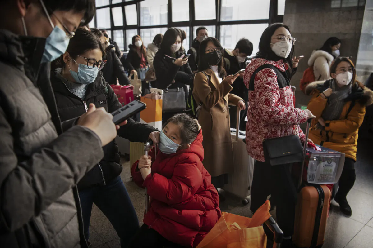Chinese travelers wear protective masks as they wait before boarding a train before the annual Spring Festival at a Beijing railway station on Jan. 23, 2020. (Kevin Frayer/Getty Images)