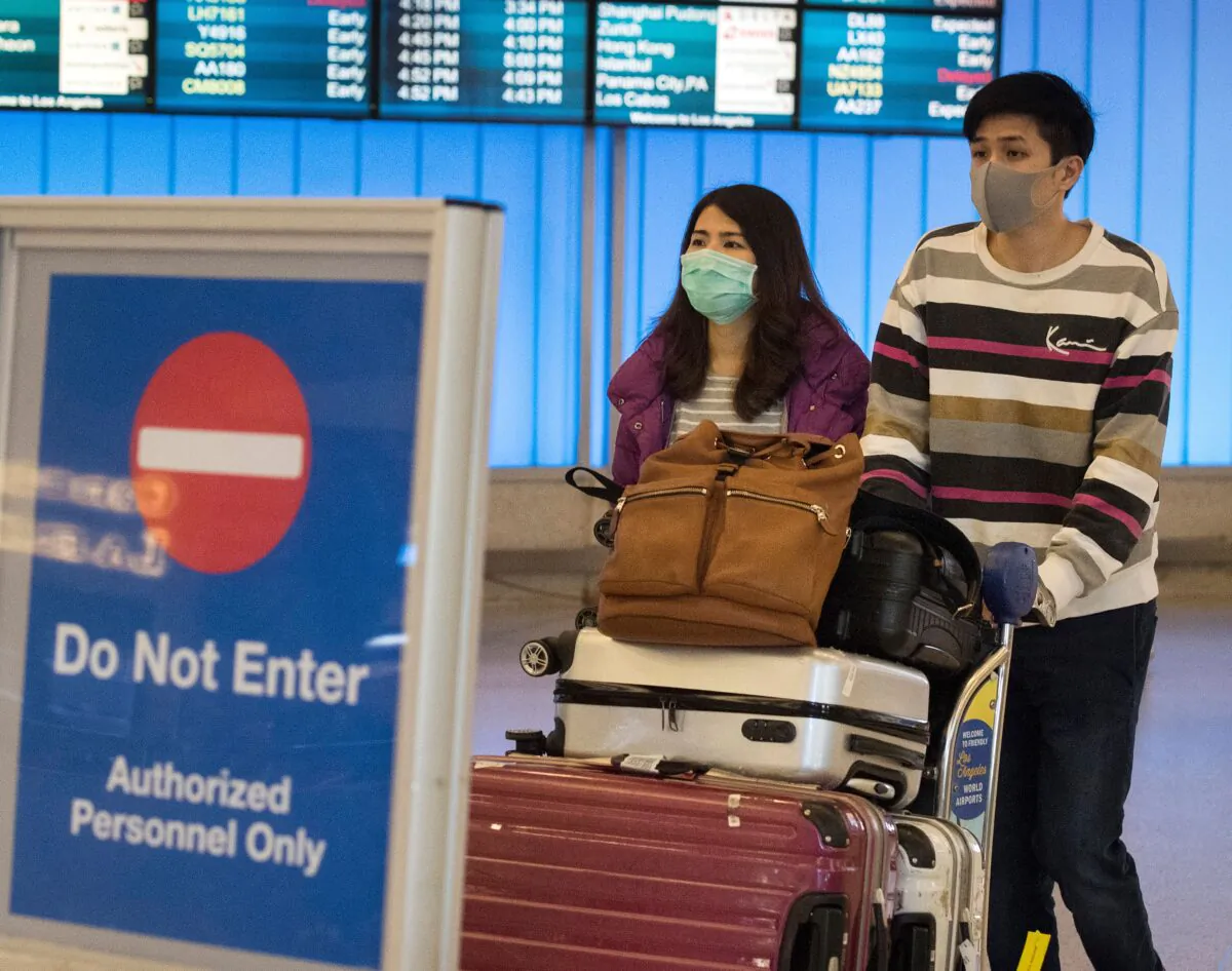 Passengers wear protective masks to protect against the spread of COVID-19 as they arrive at the Los Angeles International Airport on Jan. 22, 2020. (Mark Ralston/AFP via Getty Images)