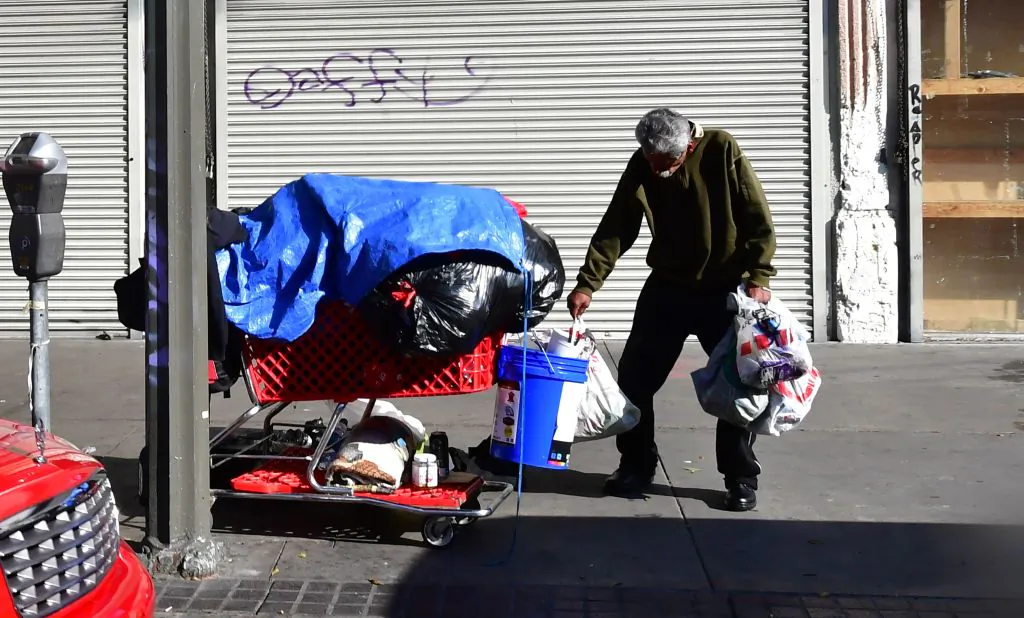 A homeless man stands with a cart of his belongings on a street in Los Angeles, Calif., on Jan. 8, 2020. (Frederic J. Brown/AFP via Getty Images)