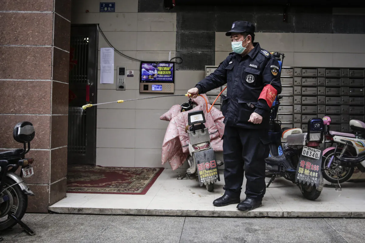A security is using alcohol to disinfect in a community in Wuhan City, China on Jan. 23, 2020. (Getty Images)
