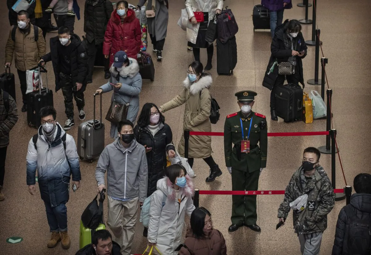 A Chinese police officer wears a protective mask as passengers, many wearing masks also, arrive to board trains at a Beijing railway station in Beijing, China on Jan. 23, 2020. (Kevin Frayer/Getty Images)