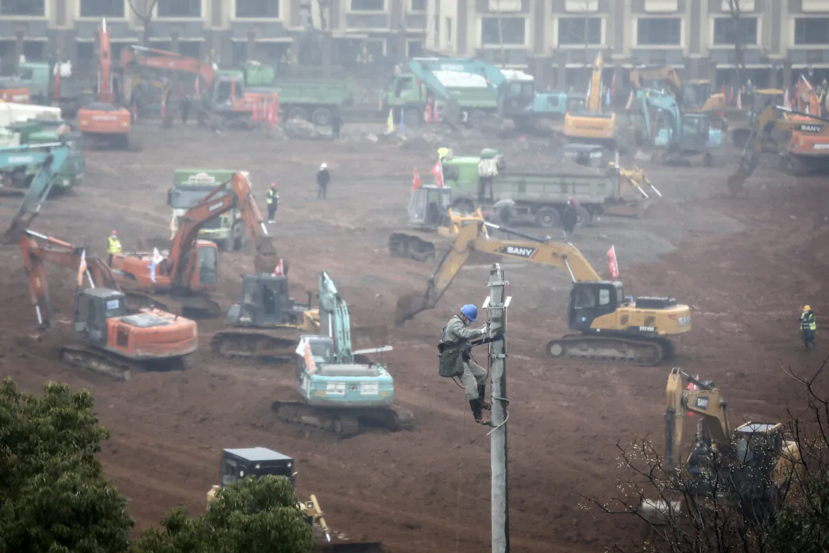 An electrician sets up wiring while workers drive excavators at the construction site of a new hospital designed to cope with the surge of 2019 Novel Coronavirus patients, in Wuhan, China on Jan. 24, 2020. (Getty Images)