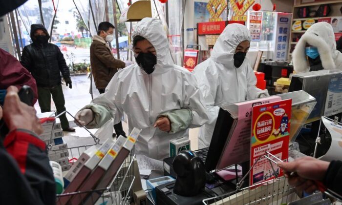 Pharmacy workers wearing protective clothes and masks serve customers in Wuhan on Jan. 25, 2020. (Hector Retamal/AFP via Getty Images)