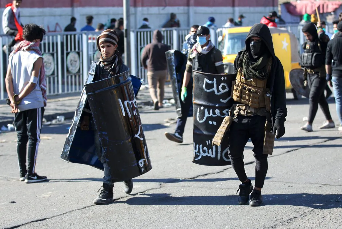 Iraqi protesters with makeshift protective gear walk by following clashes with security forces during an anti-government demonstration in Al-Khilani square in the capital Baghdad, on Jan. 26, 2020. (AHMAD AL-RUBAYE/AFP via Getty Images)