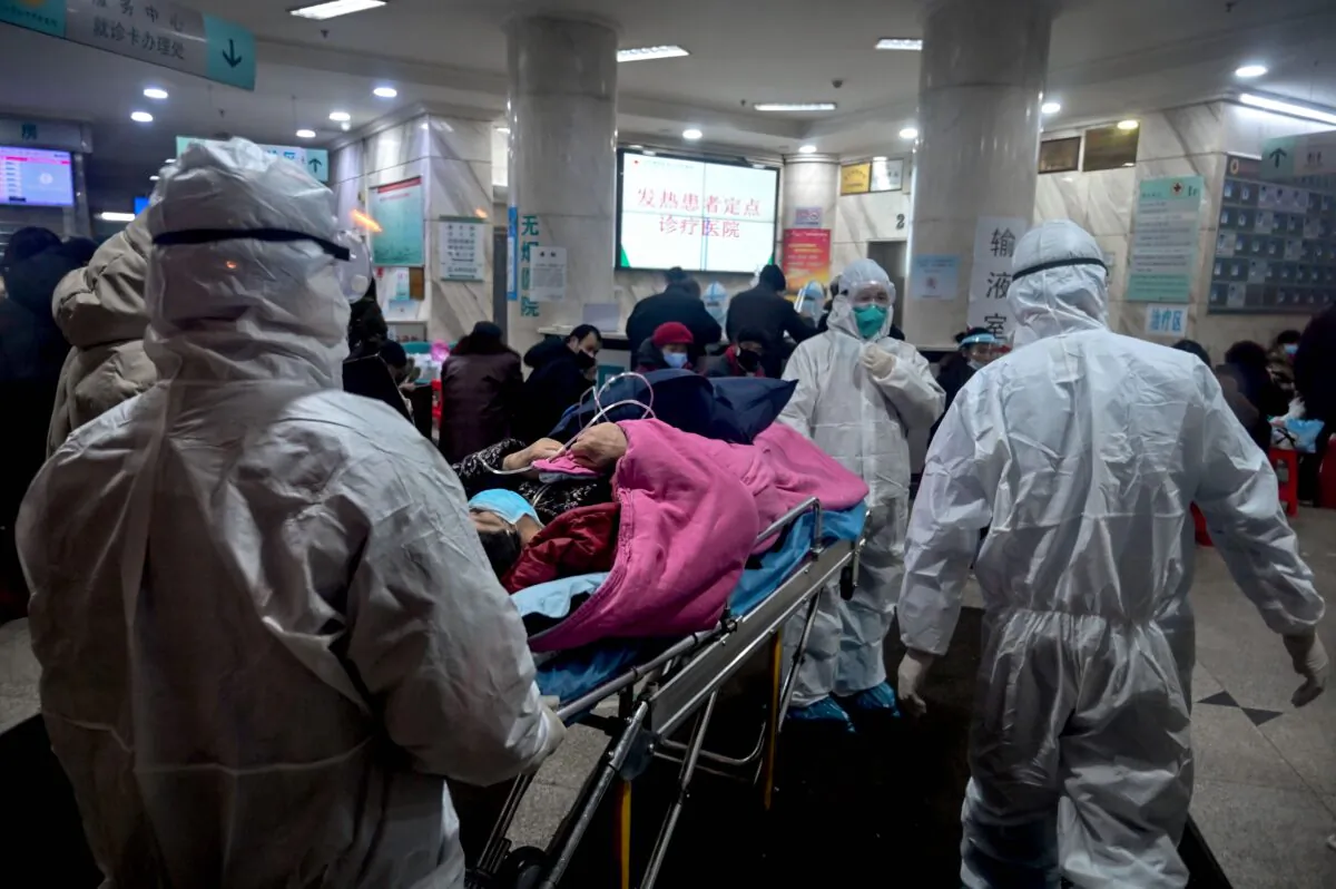 Medical staff wearing protective clothing arrive with a patient at the Wuhan Red Cross Hospital in Wuhan City, China, on Jan. 25, 2020. (Hector Retamal/AFP via Getty Images)