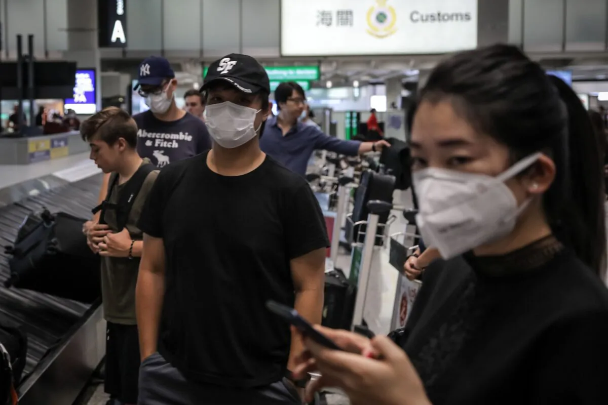 Travellers wearing face masks as a precautionary measure to protect against the outbreak of coronavirus, at Hong Kong International Airport, on Jan. 23, 2020. (Vivek Prakash/AFP via Getty Images)