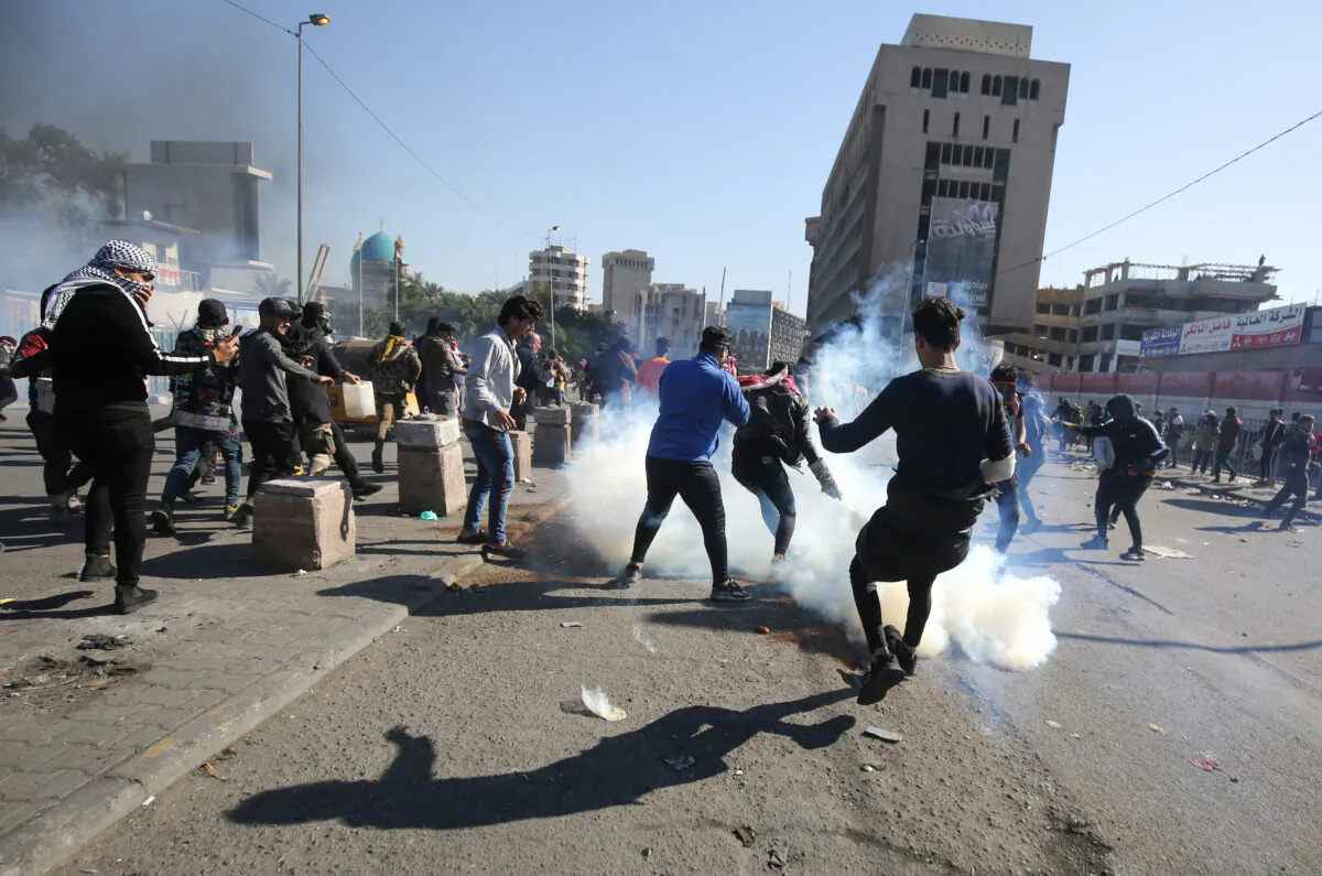 Iraqi protesters scurry to catch a tear gas canister amid clashes with security forces at an anti-regime demonstration in Al-Khillani square in the capital Baghdad, on Jan. 27, 2020. (AHMAD AL-RUBAYE/AFP via Getty Images)