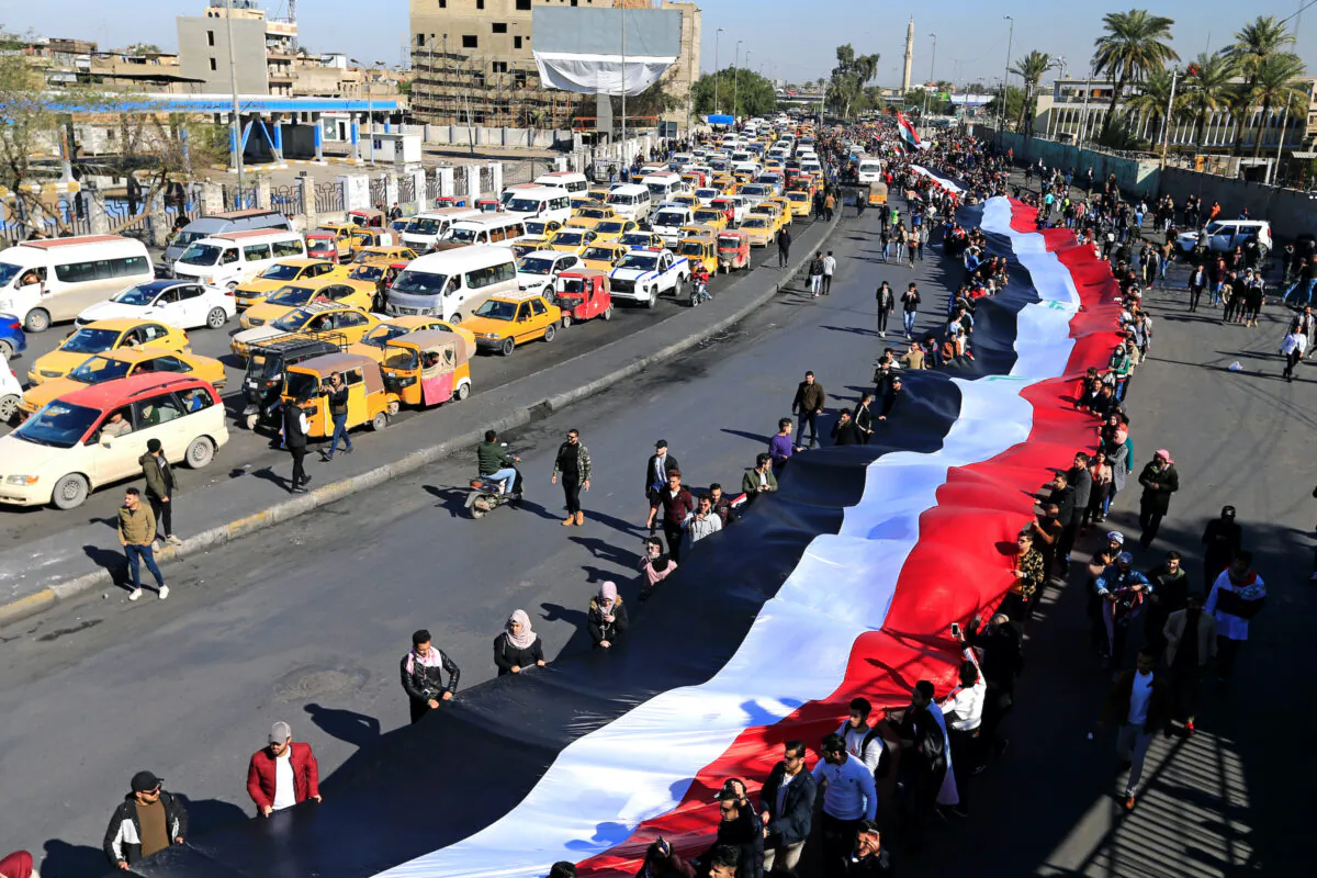 University students carry an Iraqi flag, during ongoing anti-government protests in Baghdad, Iraq on Jan. 26, 2020. (Thaier al-Sudani/Reuters)