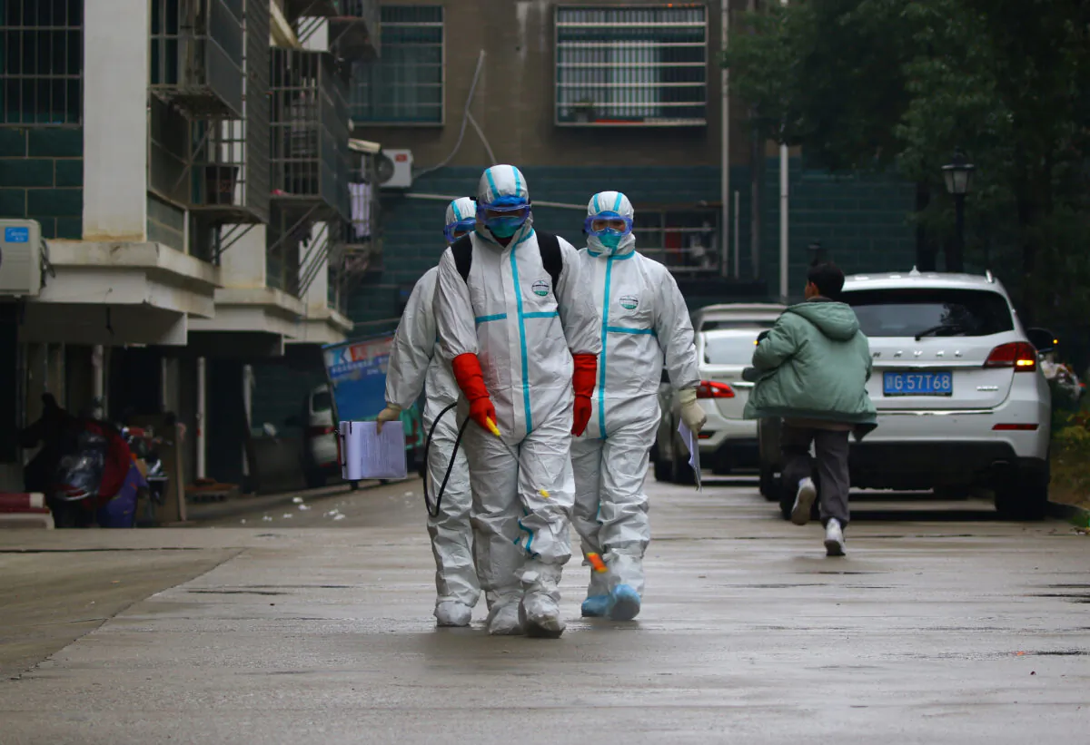 Workers from the local disease control and prevention department in protective suits disinfect a residential area following the outbreak of a new coronavirus, in Ruichang, Jiangxi Province, China on Jan. 25, 2020. (cnsphoto via Reuters)
