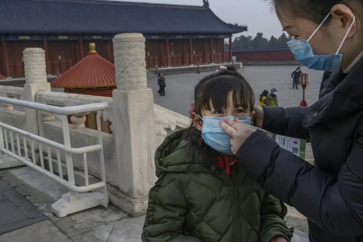 A young Chinese visitor wears a protective mask as she tours the nearly empty grounds of the Temple of Heaven in Beijing, China, on Jan. 27, 2020. (Kevin Frayer/Getty Images)