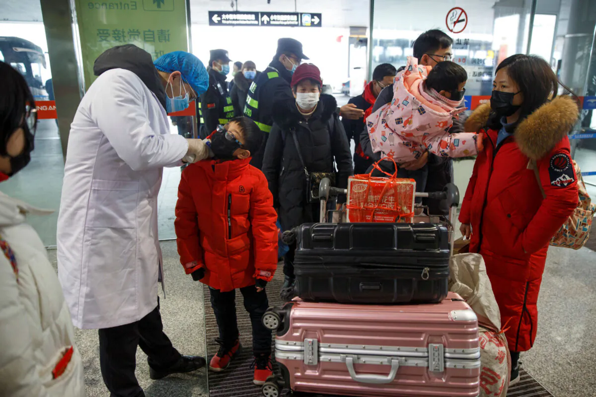 A medical official takes the body temperature of a child at the departure hall of the airport in Changsha, Hunan Province, as the country is hit by an outbreak of a new coronavirus, China, Jan. 27, 2020. (Reuters/Thomas Peter)
