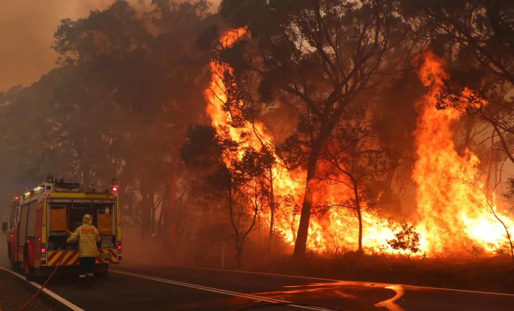 SYDNEY, AUSTRALIA - DECEMBER 19: Fire and Rescue personnel run to move their truck as a bushfire burns next to a major road and homes on the outskirts of the town of Bilpin on December 19, 2019 in Sydney, Australia. NSW Premier Gladys Berejiklian has declared a state of emergency for the next seven days with ongoing dangerous fire conditions and almost 100 bushfires burning across the state. It's the second state of emergency declared in NSW since the start of the bushfire season.  (Photo by David Gray/Getty Images)