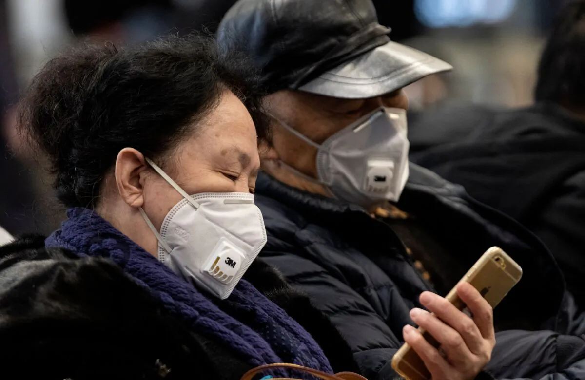 Travellers wearing protective masks rest on a bench after arriving at Beijing Capital Airport in Beijing on Jan. 21, 2020. (NOEL CELIS/AFP via Getty Images)