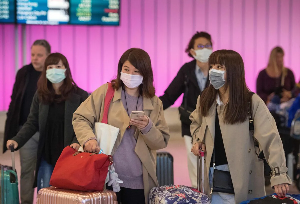 Passengers wear protective masks to protect against the spread of the Coronavirus as they arrive at the Los Angeles International Airport, Calif., on Jan. 22, 2020. (Mark Ralston/AFP via Getty Images)