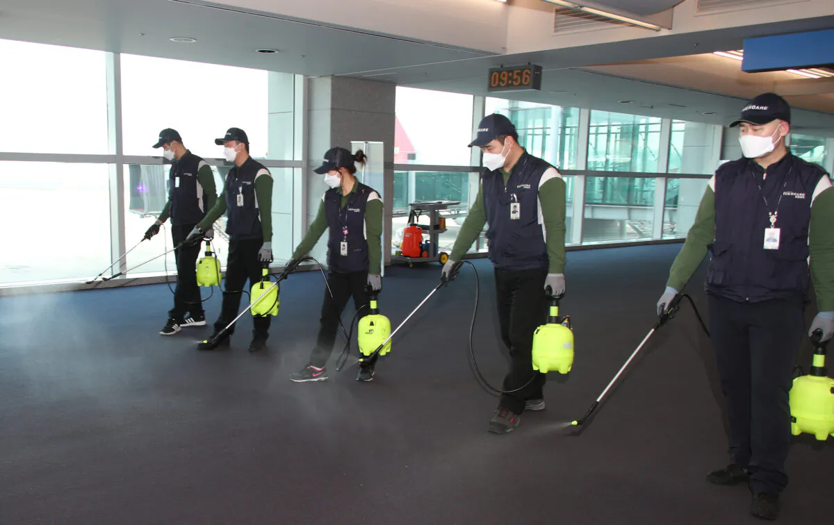 Employees from a disinfection service company sanitize the floor of Incheon International Airport in Incheon, South Korea, on Jan. 24, 2020. (Yonhap via Reuters)