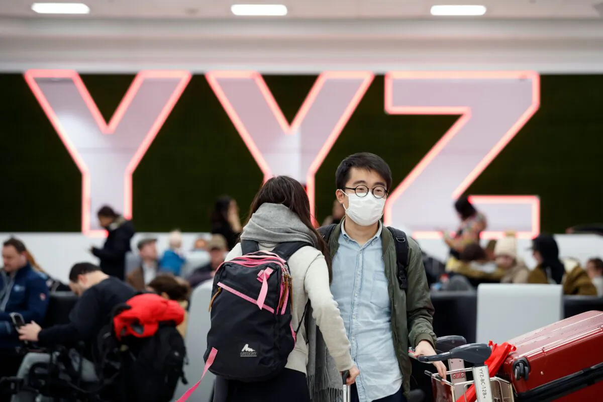 Travelers are seen wearing masks at the international arrivals area at the Toronto Pearson Airport in Toronto, Canada, on Jan. 26, 2020. (Cole Burston/AFP via Getty Images)