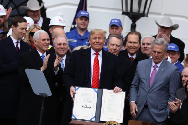 President Donald Trump holds up the signed USMCA agreement