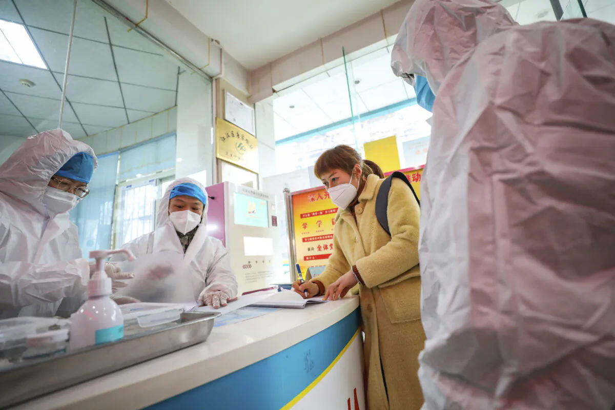 Medical workers in protective gear talk with a woman suspected of being ill with a coronavirus at a community health station in Wuhan in central China's Hubei Province, on Jan. 27, 2020. (Chinatopix via AP)