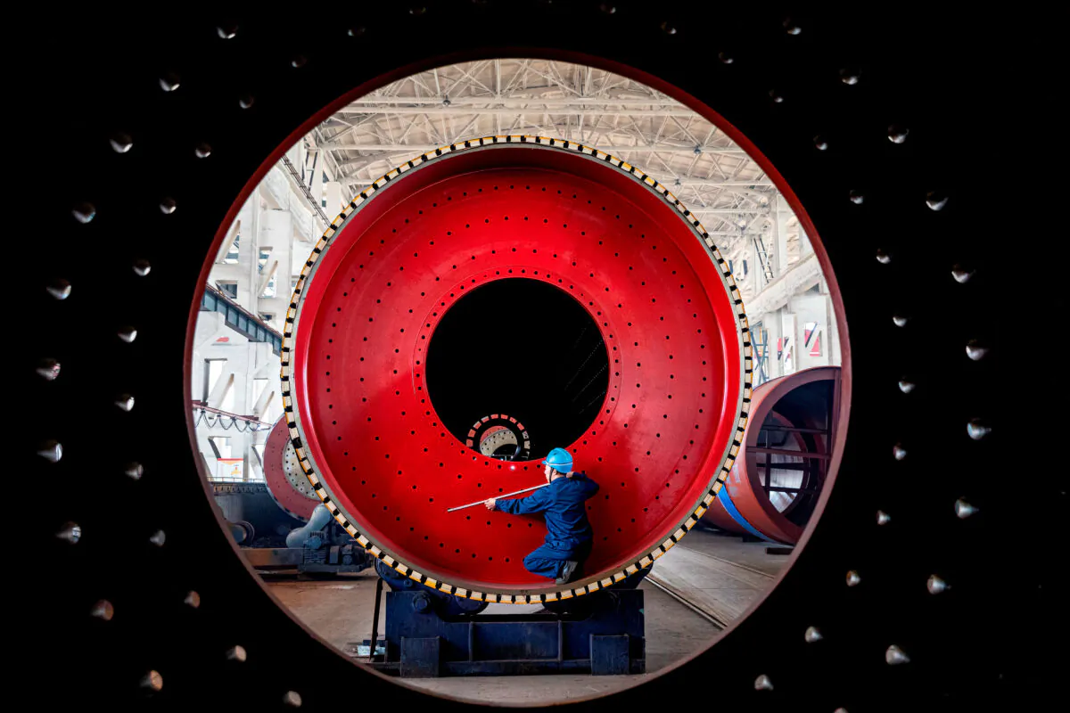 An employee measures a newly manufactured ball mill machine at a factory in Nantong, Jiangsu Province, China, on June 28, 2019. (Stringer/Reuters)