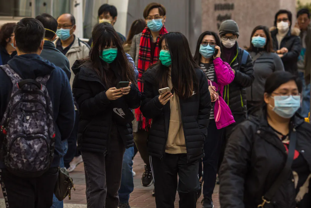 People wearing masks walk along a street in Hong Kong on Jan. 30, 2020. (Dale De La Rey/AFP via Getty Images)