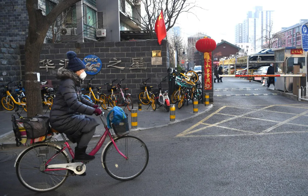 A cyclist wearing a facemask passes bicycles (C) piled up as a barricade to block a side entrance to a residential compound, forcing visitors to register with guards at the main entrance, in Beijing on Jan. 30, 2020. Noel Celis/AFP via Getty Images