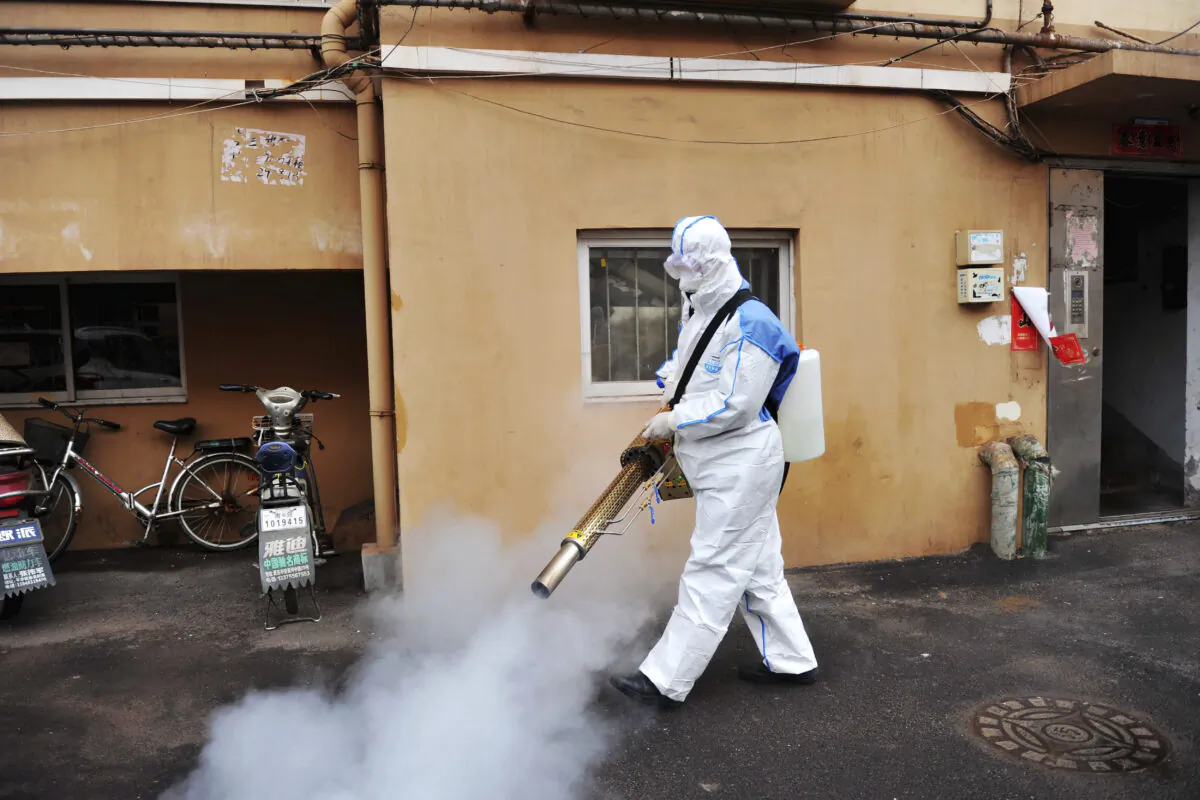 A worker wearing a protective suit sprays disinfectant in a neighborhood in Qingdao in eastern China's Shandong province on Jan. 28, 2020. (Chinatopix via AP)