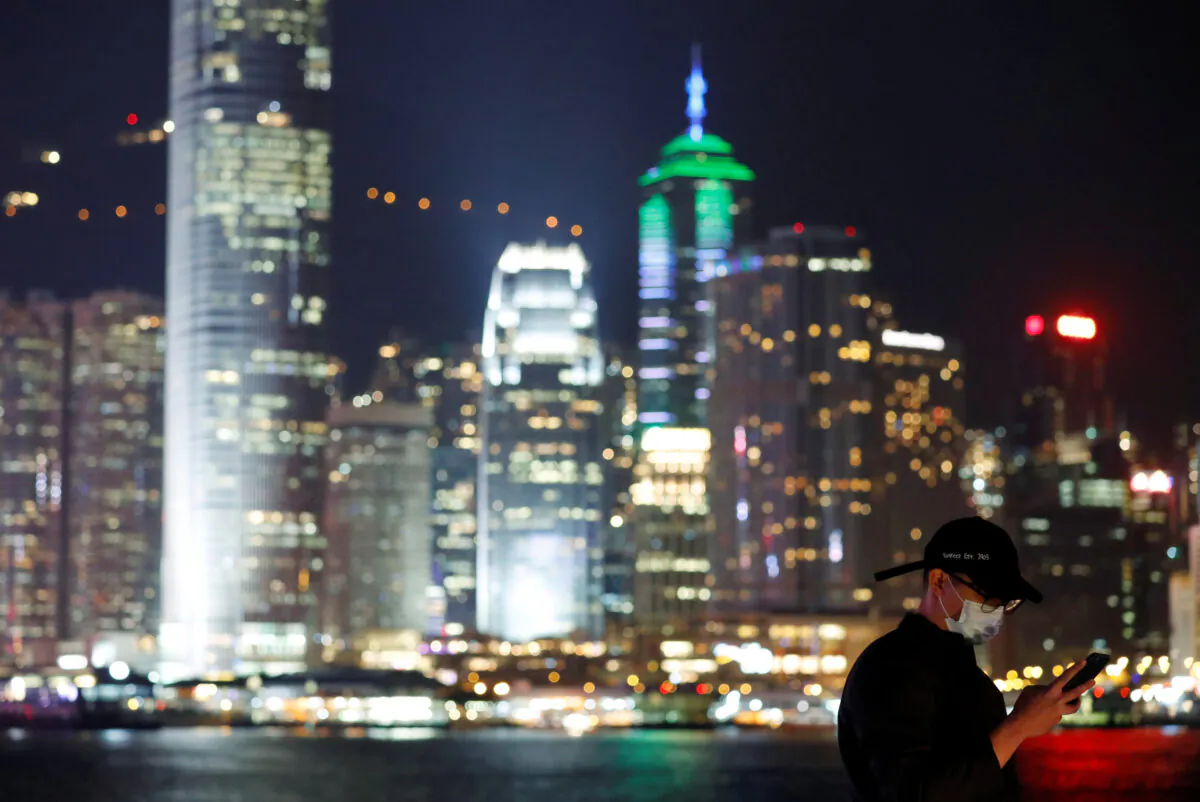 A man wears mask to prevent a new coronavirus outbreak as he uses his mobile, with skyline in the background of Hong Kong, China, on Jan. 29, 2020. (Tyrone Siu/Reuters)