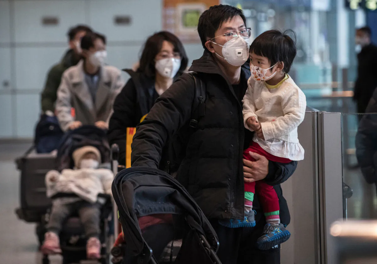 Passengers wear protective masks as they walk he their luggage in the arrivals area at Beijing Capital Airport in Beijing, China, on Jan. 30, 2020.(Kevin Frayer/Getty Images)