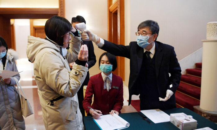 A man uses a thermometer to check the temperature of a journalist covering a meeting between Tedros Adhanom, director general of the World Health Organization, and Chinese Foreign Minister Wang Yi at the Diaoyutai State Guesthouse in Beijing, China, on Jan. 28, 2020. (Naohiko Hatta/Pool via Reuters)