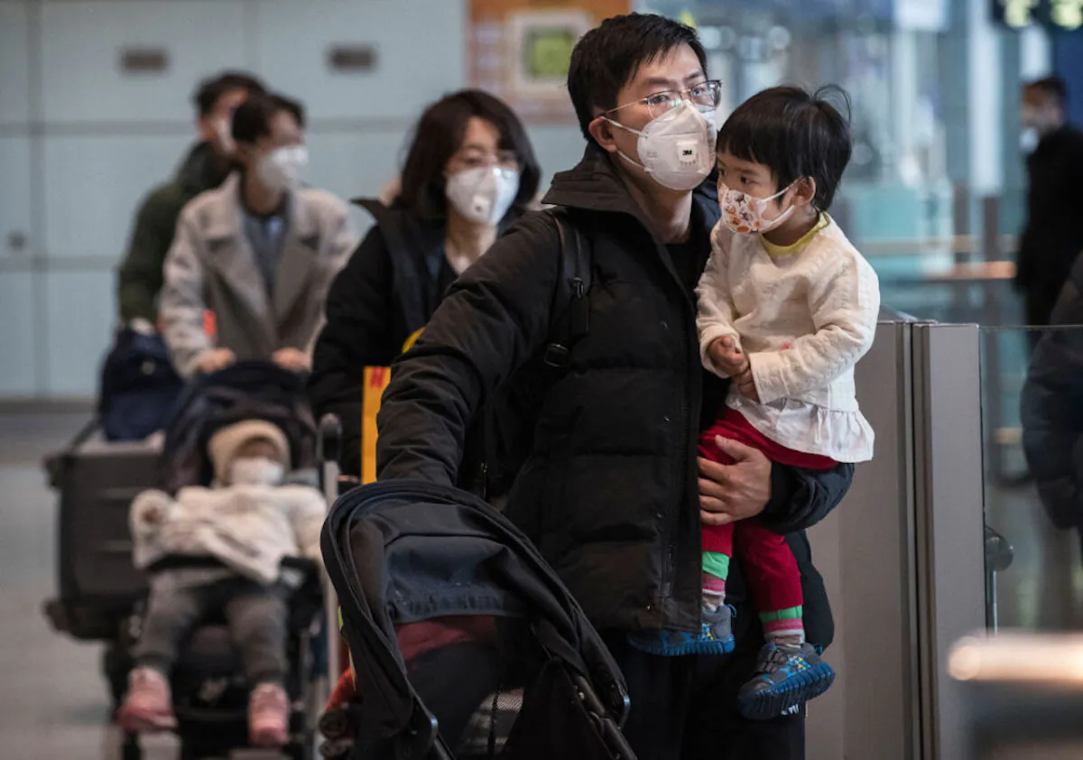 Passengers wear protective masks as they walk their luggage in the arrivals area at Beijing Capital Airport in Beijing, China, on Jan. 30, 2020. (Kevin Frayer/Getty Images)