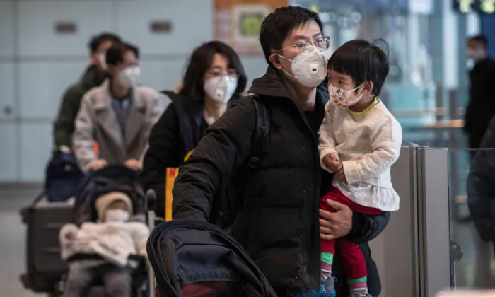Passengers wear protective masks as they walk their luggage in the arrivals area at Beijing Capital Airport in Beijing, China, on Jan. 30, 2020. (Kevin Frayer/Getty Images)