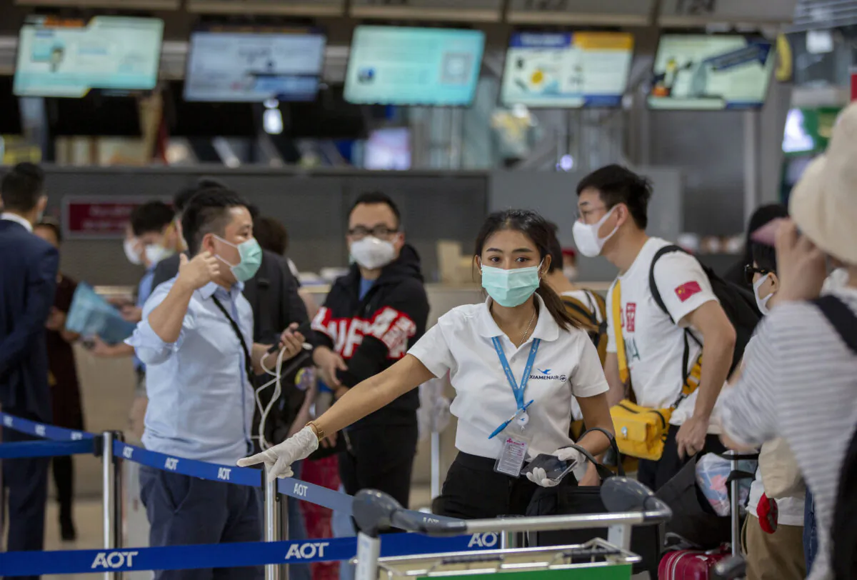 An airline staffer guides Chinese tourists who are in line to get a seat on a flight to Wuhan at Suvarnabhumi airport, Bangkok, Thailand, on Jan. 31, 2020. (Gemunu Amarasinghe/AP)
