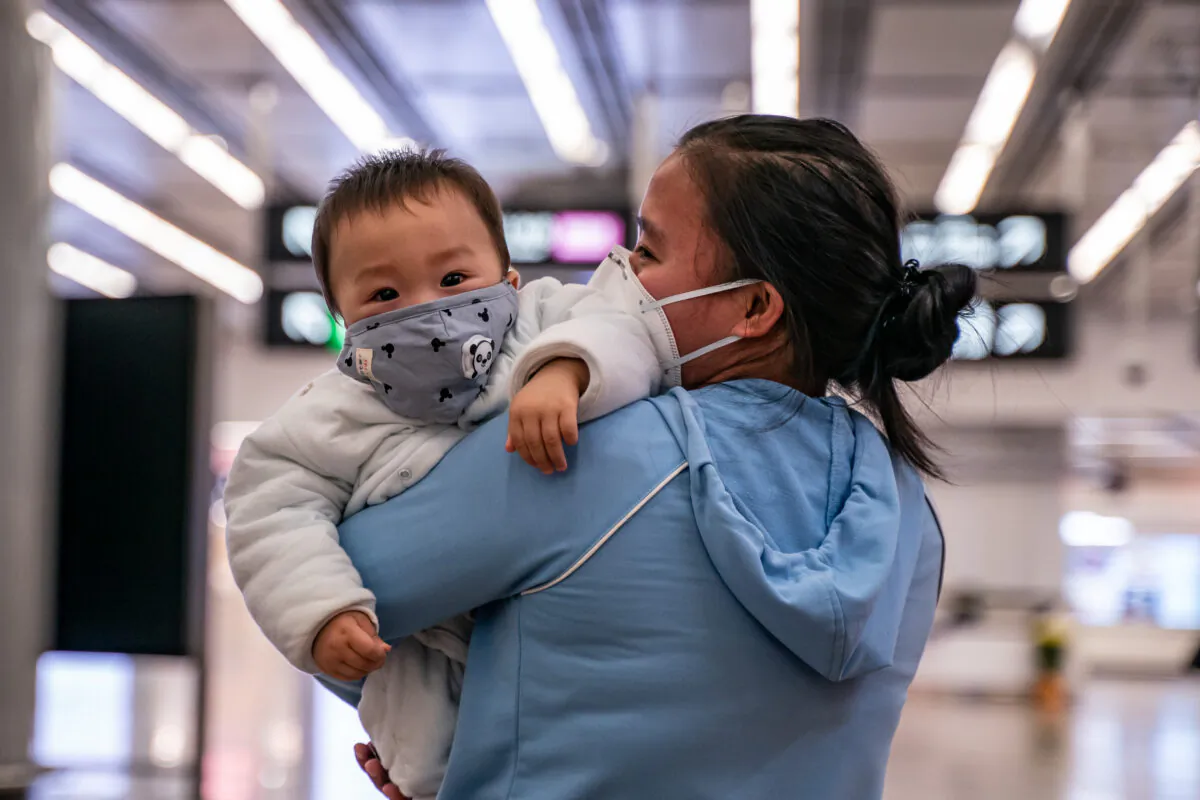 A woman carries a baby wearing a protective mask as they exit the arrival hall at Hong Kong High Speed Rail Station in Hong Kong, on Jan. 29, 2020. (Anthony Kwan/Getty Images)