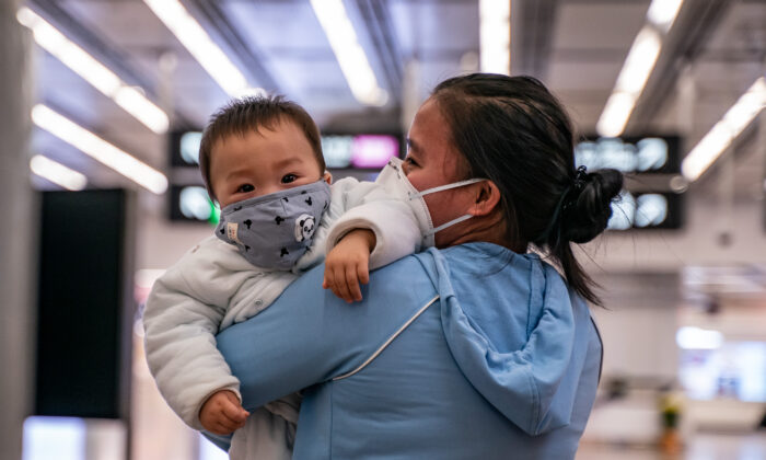 A woman carries a baby wearing a protective mask as they exit the arrival hall at Hong Kong High Speed Rail Station in Hong Kong, on Jan. 29, 2020. (Anthony Kwan/Getty Images)
