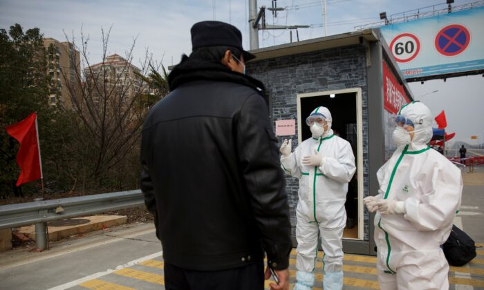 Hospital staff in protective clothing talk to a police officer at a checkpoint to the Hubei province exclusion zone at the Jiujiang Yangtze River Bridge in Jiujiang, Jiangxi province, China, as the country is hit by an outbreak of a new coronavirus on Feb. 1, 2020. (Thomas Peter/Reuters)