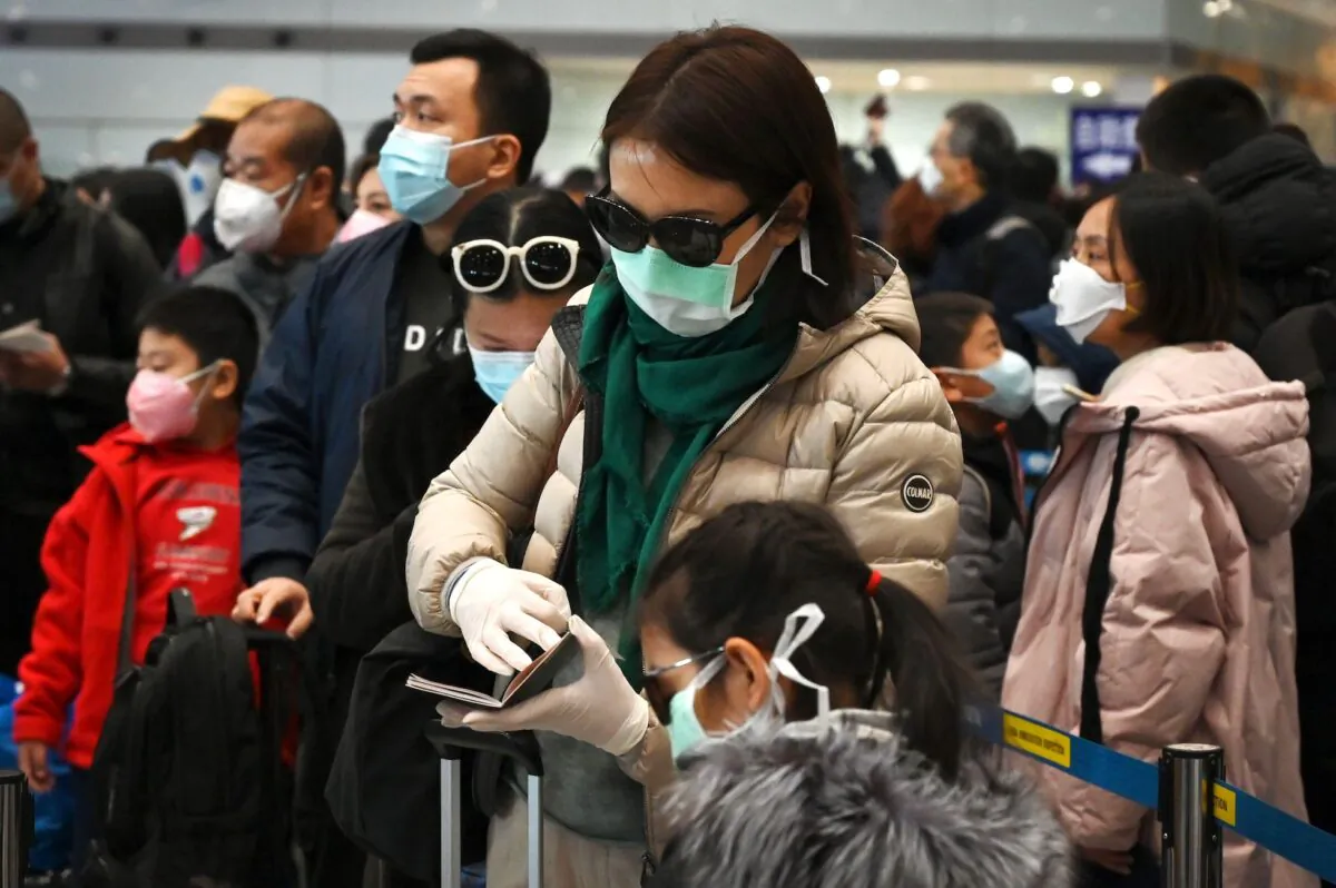 A woman wears a protective face mask and gloves while waiting to go through immigration at Beijing airport on Feb. 1, 2020. (Greg Baker/AFP via Getty Images)