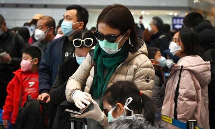 A woman wears a protective face mask and gloves while waiting to go through immigration at Beijing airport on Feb. 1, 2020. (Greg Baker/AFP via Getty Images)