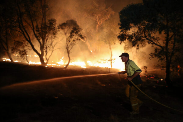 A firefighter works to extinguish flames after a bushfire burnt through the area in Bredbo
