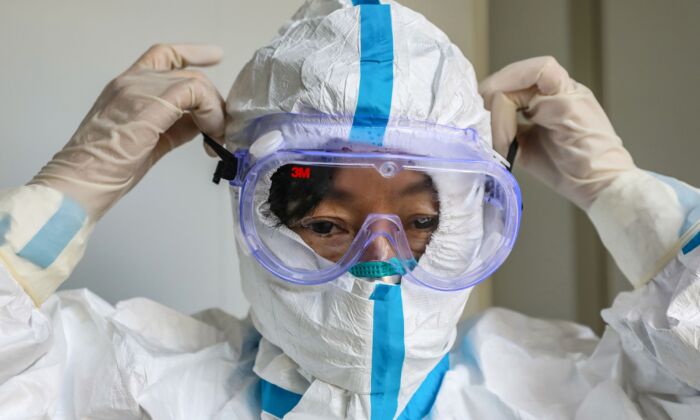 A doctor putting on a pair of protective glasses before entering the isolation ward at a hospital in Wuhan, China on Jan. 30, 2020. (STR/AFP via Getty Images)