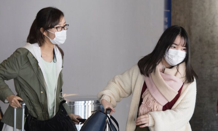Passengers wear face masks to protect against the spread of the Coronavirus as they arrive on a flight from Asia, at Los Angeles International Airport, Calif., on Feb. 1, 2020. (Mark Ralston/AFP via Getty Images)