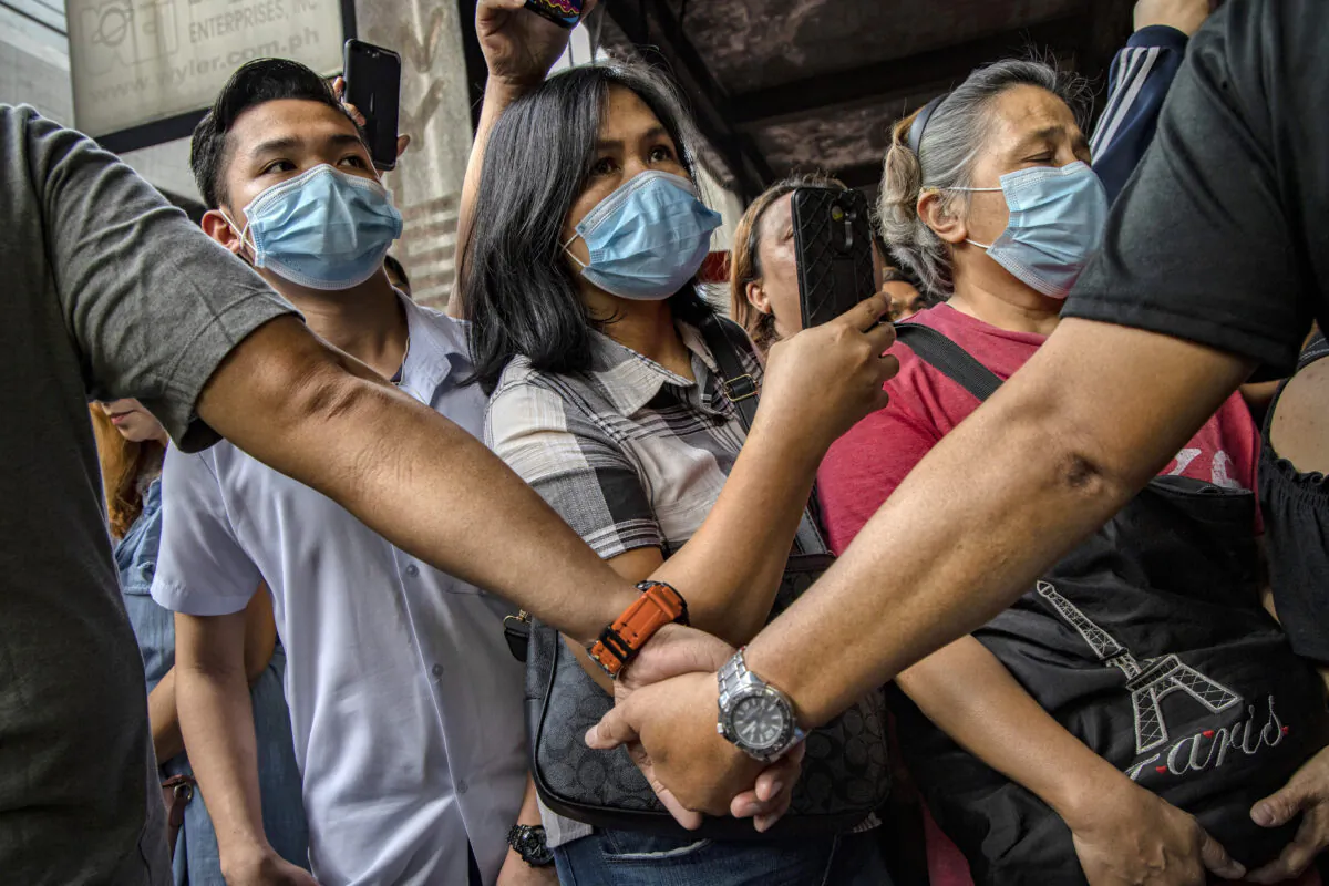 Police officers stand guard as Filipinos hoping to buy face masks crowd outside a medical supply shop that was raided by police for allegedly hoarding and overpricing the masks, as public fear over China's Wuhan Coronavirus grows in Manila, Philippines, on Jan. 31, 2020. (Ezra Acayan/Getty Images)