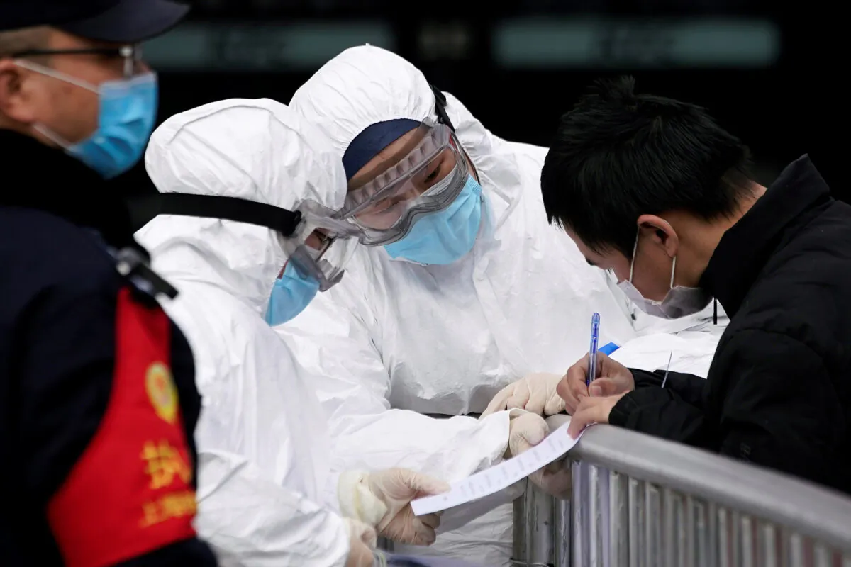 Staff members wearing protective masks check a passenger at Shanghai railway station in Shanghai, China, as the country is hit by an outbreak of a new coronavirus, on Feb. 2, 2020. (Aly Song/Reuters)