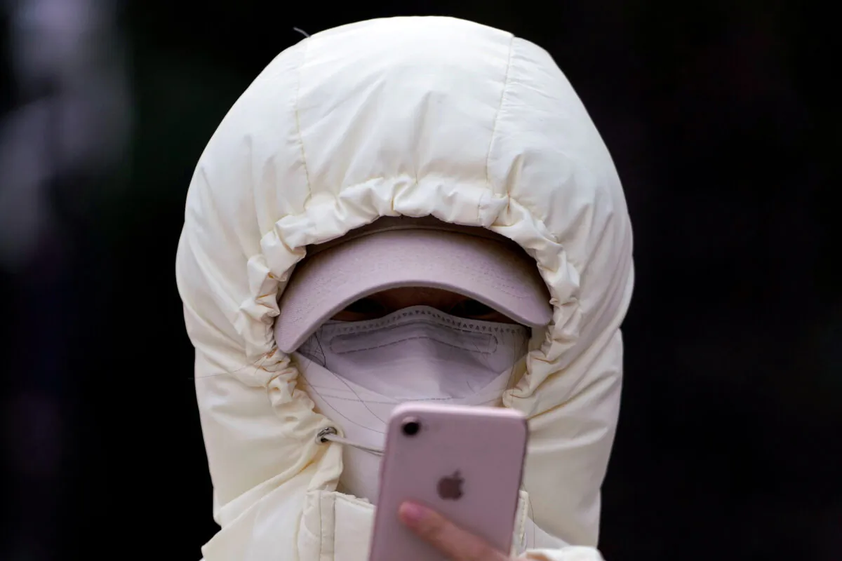 A woman wearing a mask checks her mobile phone in Shanghai, China on Jan. 29, 2020. (Aly Song/Reuters)