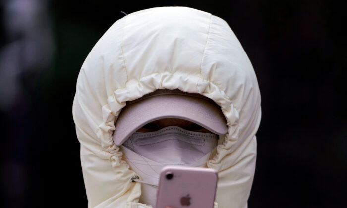 A woman wearing a mask checks her mobile phone in Shanghai, China on Jan. 29, 2020. (Aly Song/Reuters)