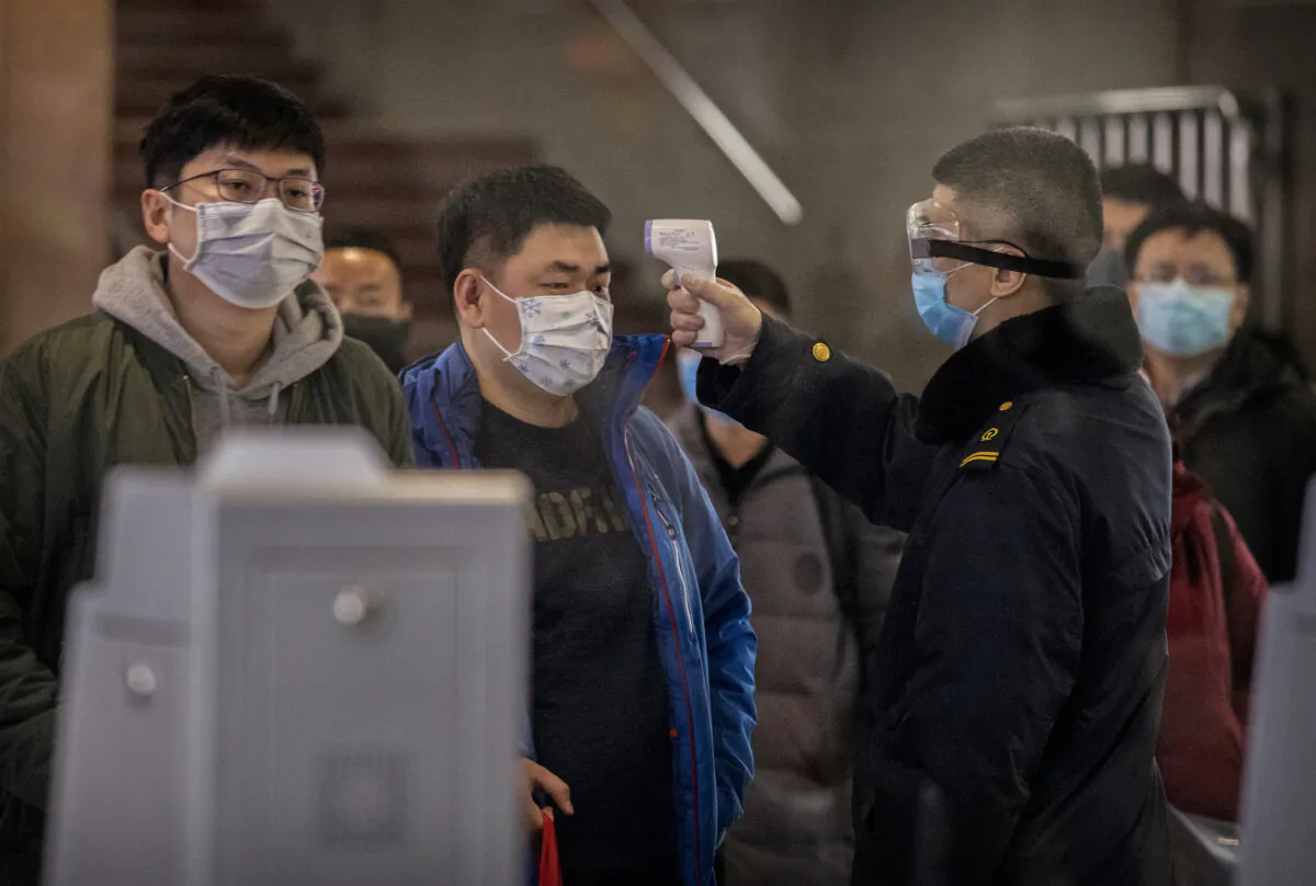 A Chinese passenger who just arrived on the last bullet train from Wuhan to Beijing is checked for a fever by a health worker at a Beijing railway station in Beijing on Jan. 23, 2020. (Kevin Frayer/Getty Images)