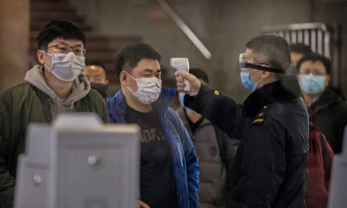A Chinese passenger who just arrived on the last bullet train from Wuhan to Beijing is checked for a fever by a health worker at a Beijing railway station in Beijing on Jan. 23, 2020. (Kevin Frayer/Getty Images)